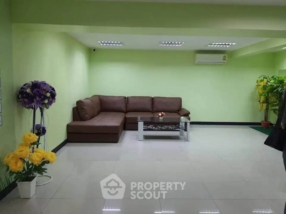 Spacious living room with modern brown sectional sofa and vibrant green walls.