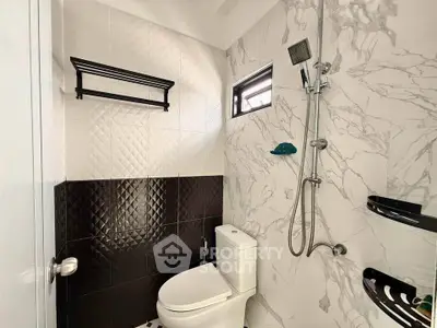 Modern bathroom with stylish black and white tiles and sleek shower fixtures.