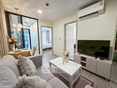 Modern living room with cozy decor and open view to bedroom, featuring sleek furniture and air conditioning.