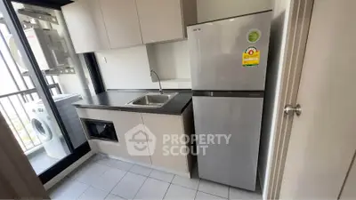 Modern kitchen with sleek cabinetry, stainless steel fridge, and balcony access, perfect for urban living.