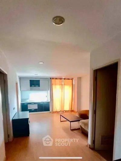 Spacious living room with natural light and modern kitchen area