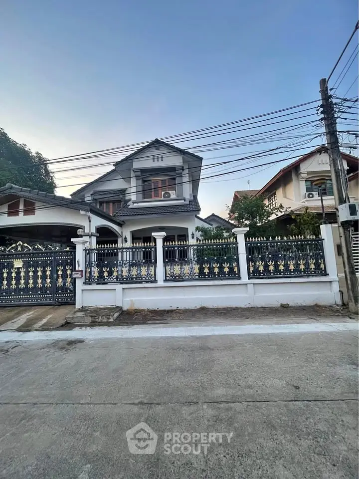 Charming two-story house with decorative fence and spacious driveway in a serene neighborhood.