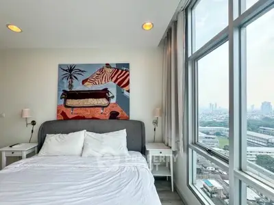 Modern bedroom with large windows offering stunning city views and stylish decor.