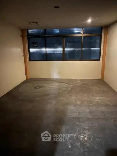 Spacious empty room with large window and tiled floor, ideal for customization.
