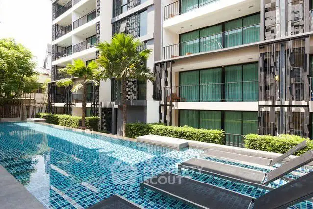 Modern apartment building with poolside view and lush greenery
