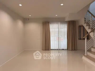 Spacious empty living room with elegant staircase and large windows