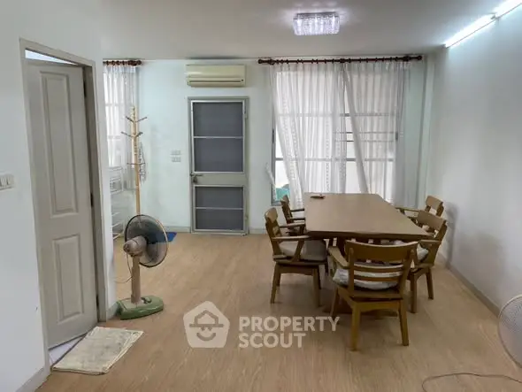 Spacious dining area with wooden table and chairs, featuring natural light and modern decor.