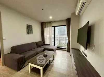 Modern living room with large sofa, flat-screen TV, and city view balcony in a stylish apartment.