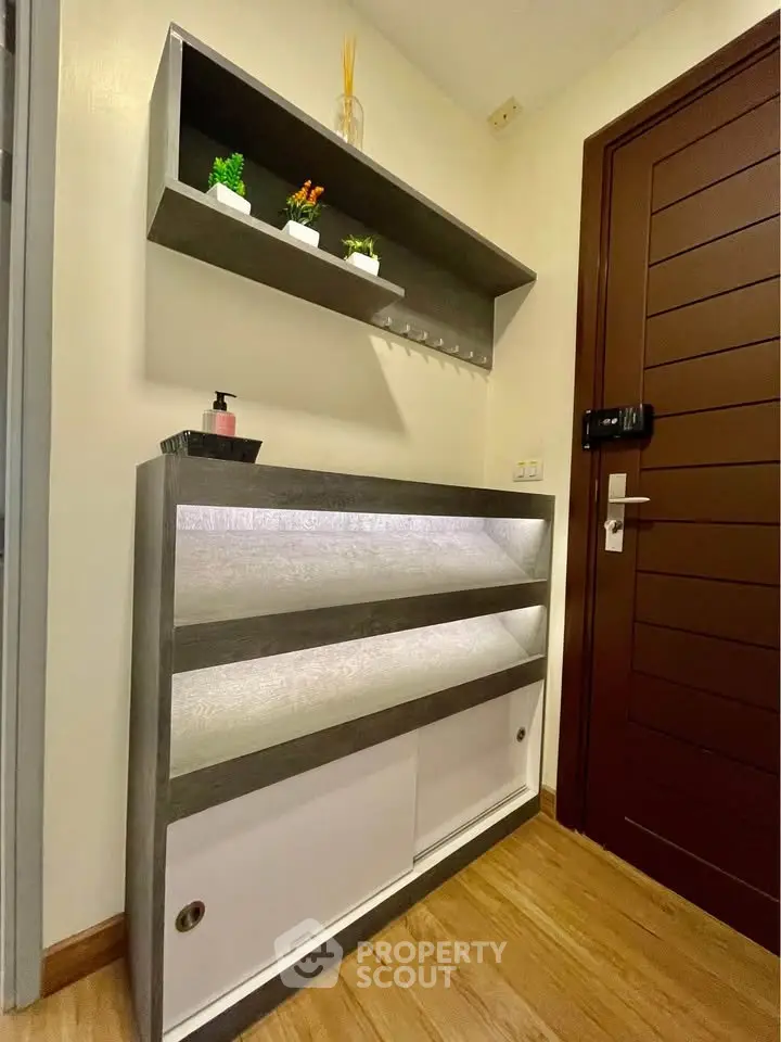 Modern entryway with sleek storage and decorative shelving in a stylish apartment.