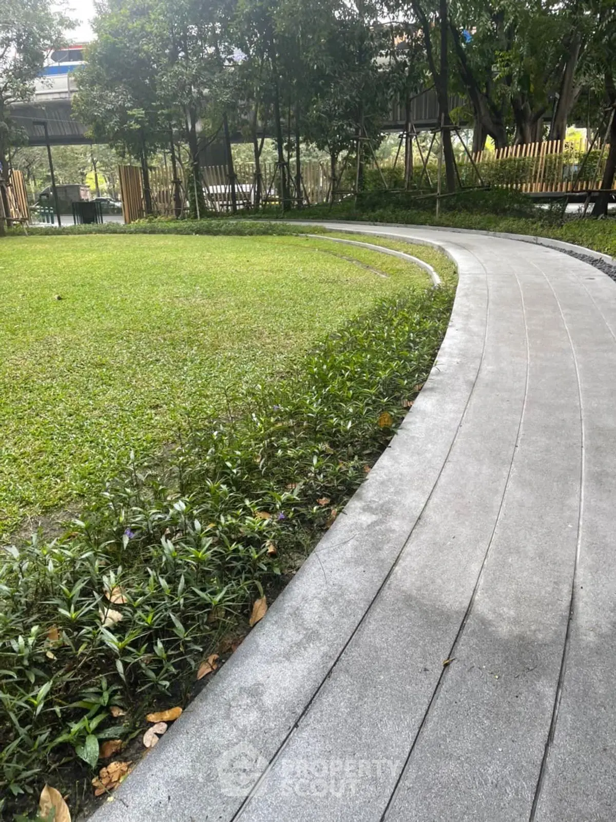 Serene garden pathway with lush greenery and trees, perfect for relaxation and outdoor enjoyment.