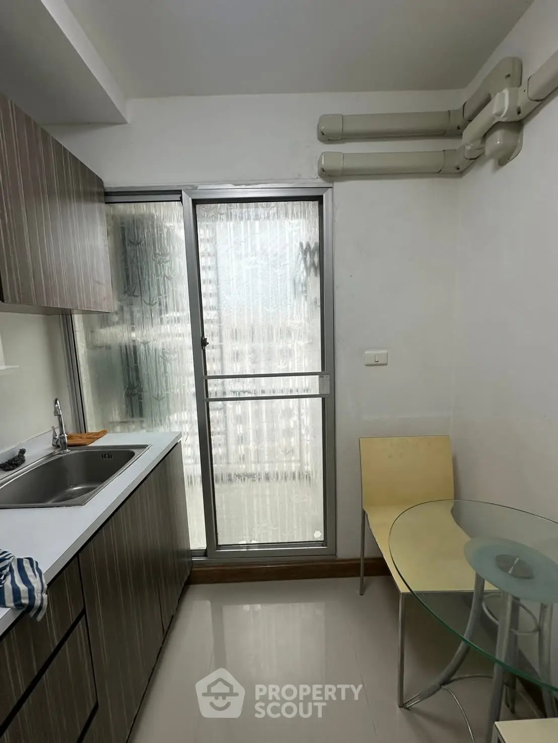 Compact kitchen with modern design and glass table, featuring a sleek closed layout.