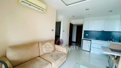 Modern living room with beige sofa and compact kitchen in open layout apartment.