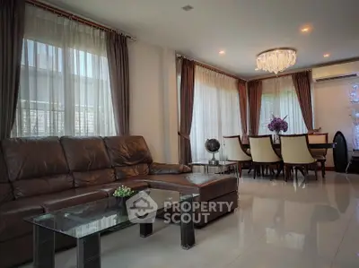 Elegant living room with leather sofa, glass coffee table, and dining area with chandelier.