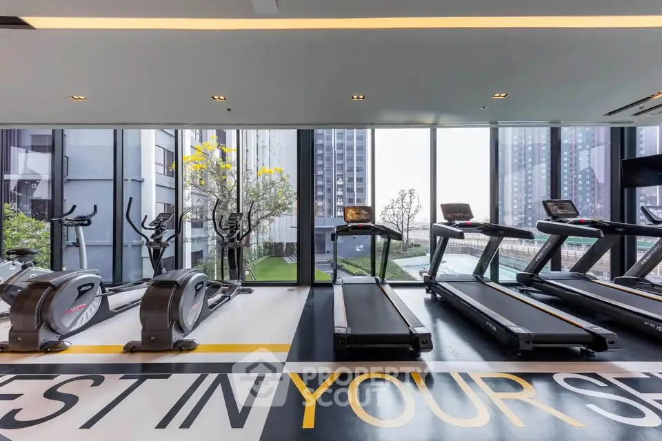 Modern gym with large windows and city view in luxury apartment building.