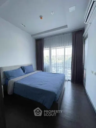 Spacious bedroom with large window and elegant curtains, featuring a comfortable bed and modern decor.
