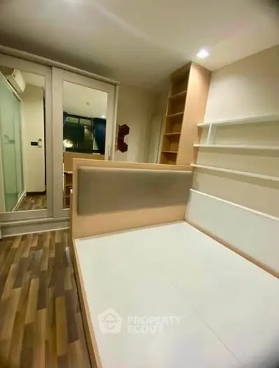 Modern bedroom with stylish wooden flooring and built-in storage solutions.
