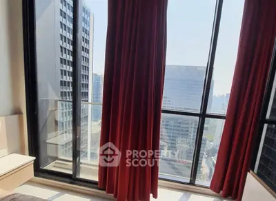 Stunning city view from high-rise apartment with floor-to-ceiling windows and elegant red curtains.
