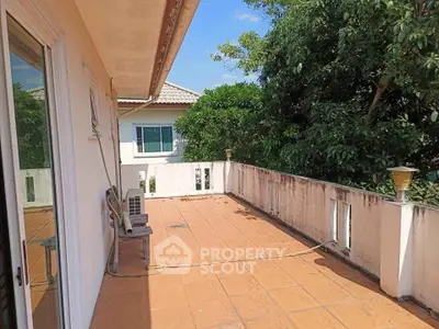 Spacious balcony with tiled flooring and lush greenery view, perfect for outdoor relaxation.