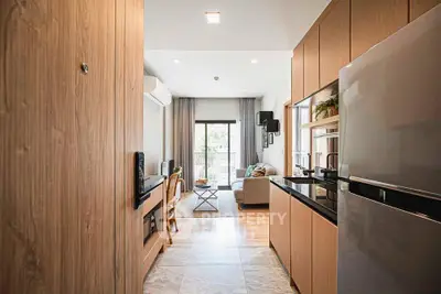 Modern open-layout kitchen leading to a cozy living room with natural light and stylish decor.
