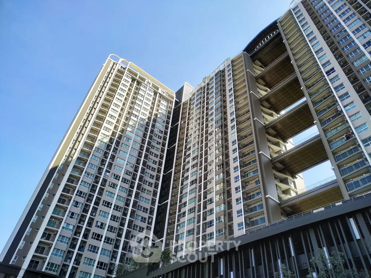 Modern high-rise residential building with sleek architecture and expansive windows under clear blue sky.