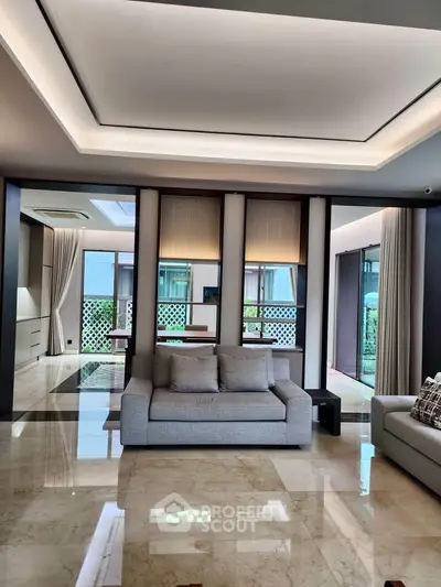 Luxurious modern living room with elegant decor and large windows offering natural light.