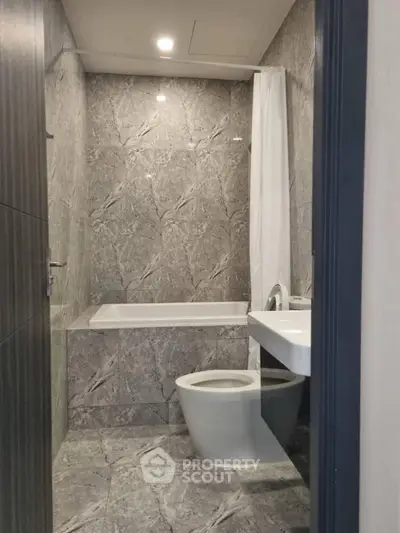 Modern bathroom with marble tiles and bathtub in luxury apartment