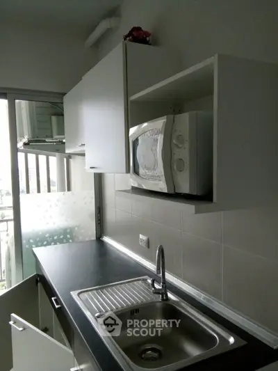 Modern kitchen with sleek cabinetry and built-in microwave, featuring a stainless steel sink and city view.