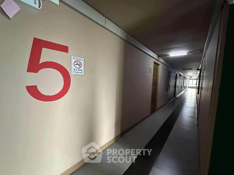 Dimly lit corridor with numbered wall and doors, typical in apartment buildings.
