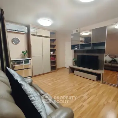 Modern living room with sleek furniture and wooden flooring, featuring a stylish entertainment center and cozy seating.