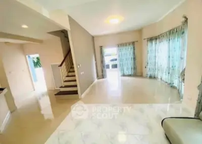 Spacious living room with elegant staircase and large windows in modern home