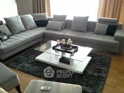 Modern living room with stylish gray sectional sofa and glass coffee table.