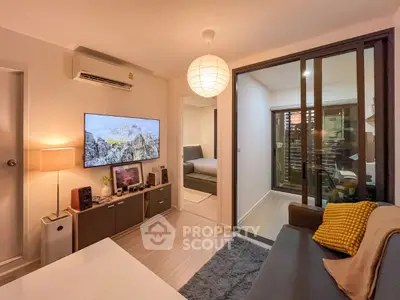Cozy living room with modern decor and large TV, adjacent to a bedroom, perfect for urban living.
