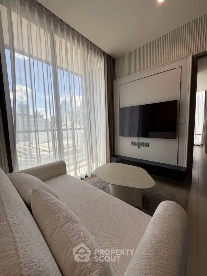 Modern living room with city view, featuring sleek furniture and large windows for natural light.