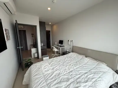 Modern bedroom with cozy bed, sleek desk, and neutral decor in a stylish apartment.