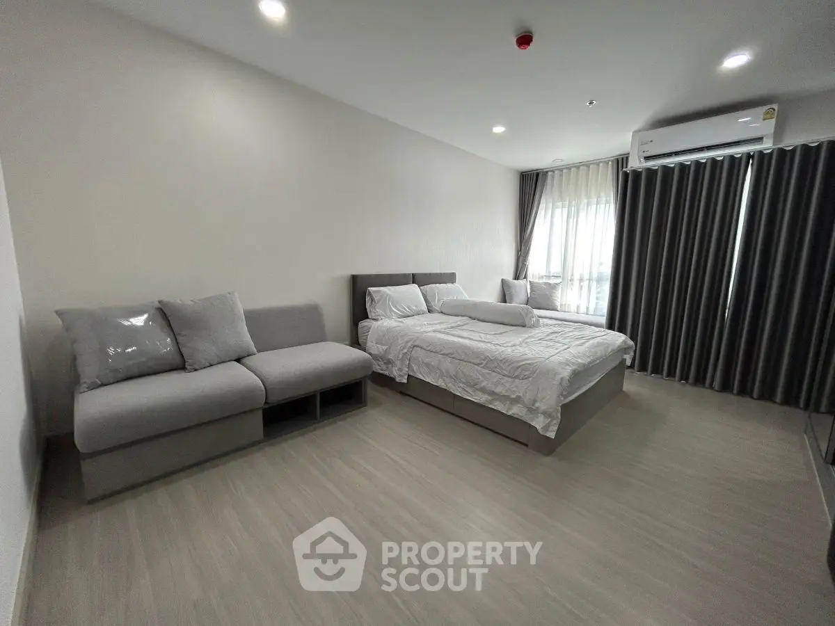 Modern bedroom with cozy bed and stylish sofa in a minimalist design apartment.