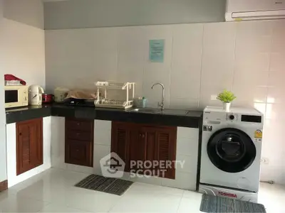 Modern kitchen with washing machine and sleek appliances in a cozy home setting.