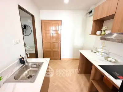 Modern kitchen with sleek wooden cabinets and marble countertops, featuring a built-in sink and stylish decor.