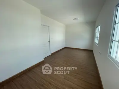 Spacious empty room with wooden flooring and white walls, perfect for customization.
