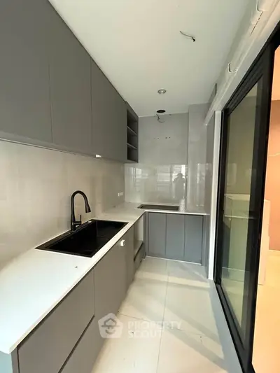 Modern kitchen with sleek cabinetry and large window for natural light