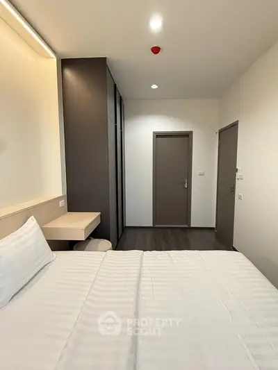 Modern bedroom with sleek design and minimalist decor, featuring a comfortable bed and built-in storage.