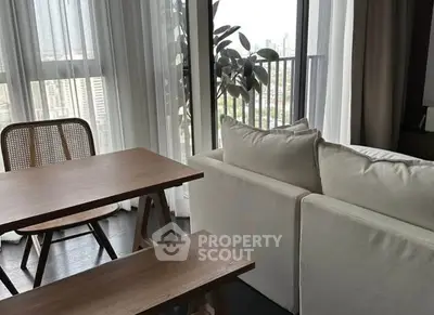 Modern living room with cozy sofa and dining area near large windows with city view.