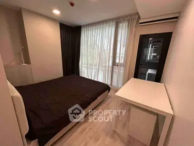 Modern bedroom with large window and sleek furnishings in a stylish apartment.