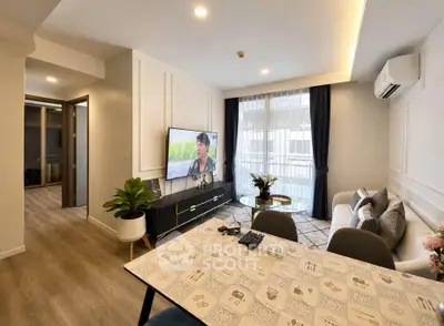 Modern living room with stylish decor and natural light, featuring a cozy sofa and wall-mounted TV.