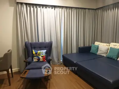 Cozy living room with modern blue sofa and stylish armchair, perfect for relaxation.