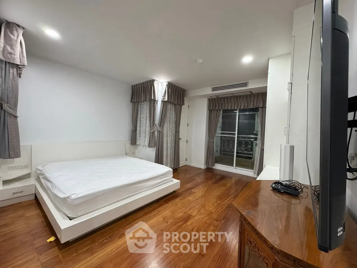 Spacious bedroom with wooden flooring and elegant curtains in modern apartment