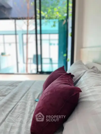 Luxurious bedroom with plush pillows and floor-to-ceiling windows offering serene views.