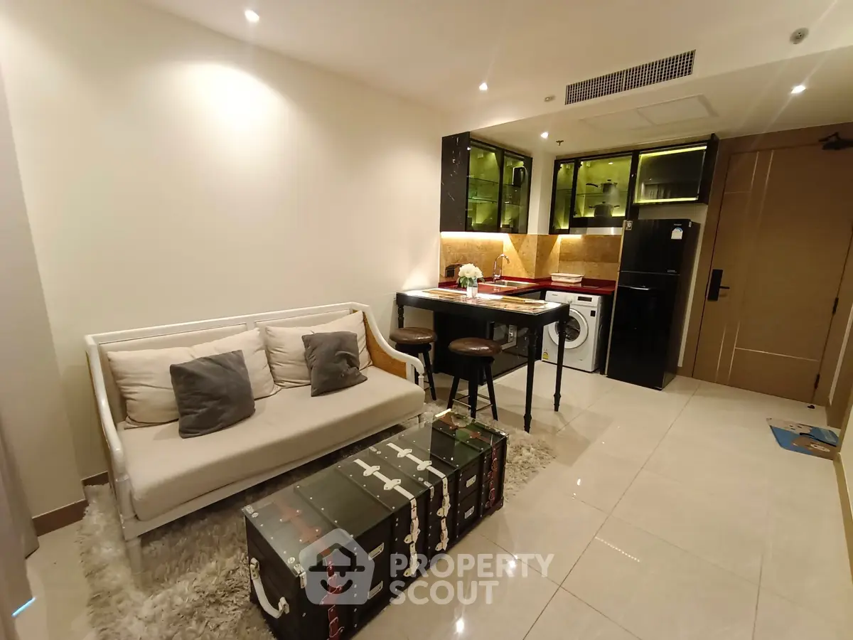 Modern living room with open kitchen, featuring stylish furniture and appliances.