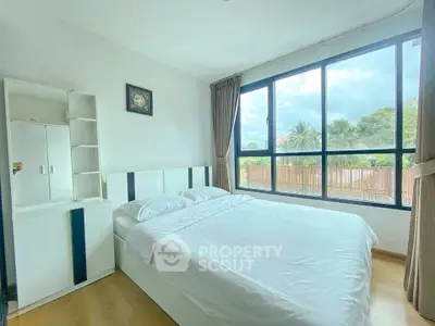 Bright and airy bedroom with large windows and modern furnishings, offering a serene view.