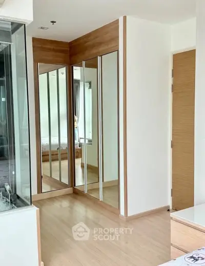 Spacious bedroom with mirrored closet doors and wooden flooring in modern apartment