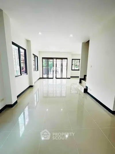 Spacious modern living room with large windows and glossy tiled floors